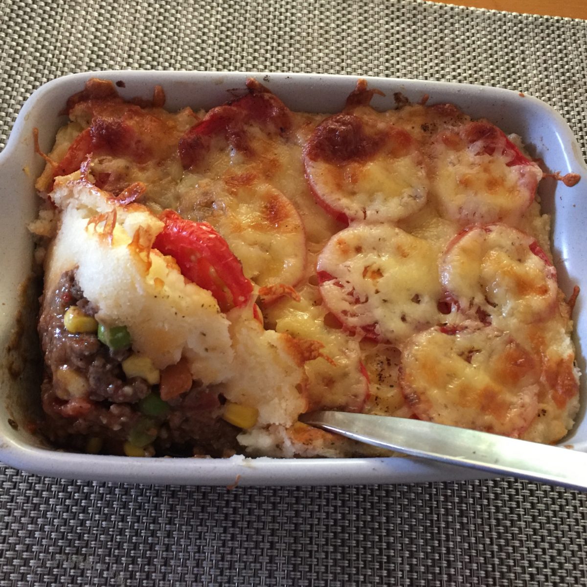 Beef shepherd's pie, savoury beef and vegetables topped with mashed potato - sliced tomatoes and melted cheese