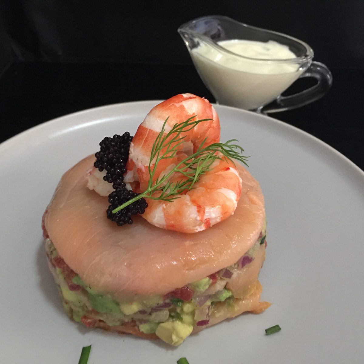 layers of smoked salmon lemony avocado salsa topped with 3 fresh ly peeled prawns and a little black caviar with a sprig of dill and lemony mayonnaise dressing with chopped dill or chives on the side by cooking meals for one