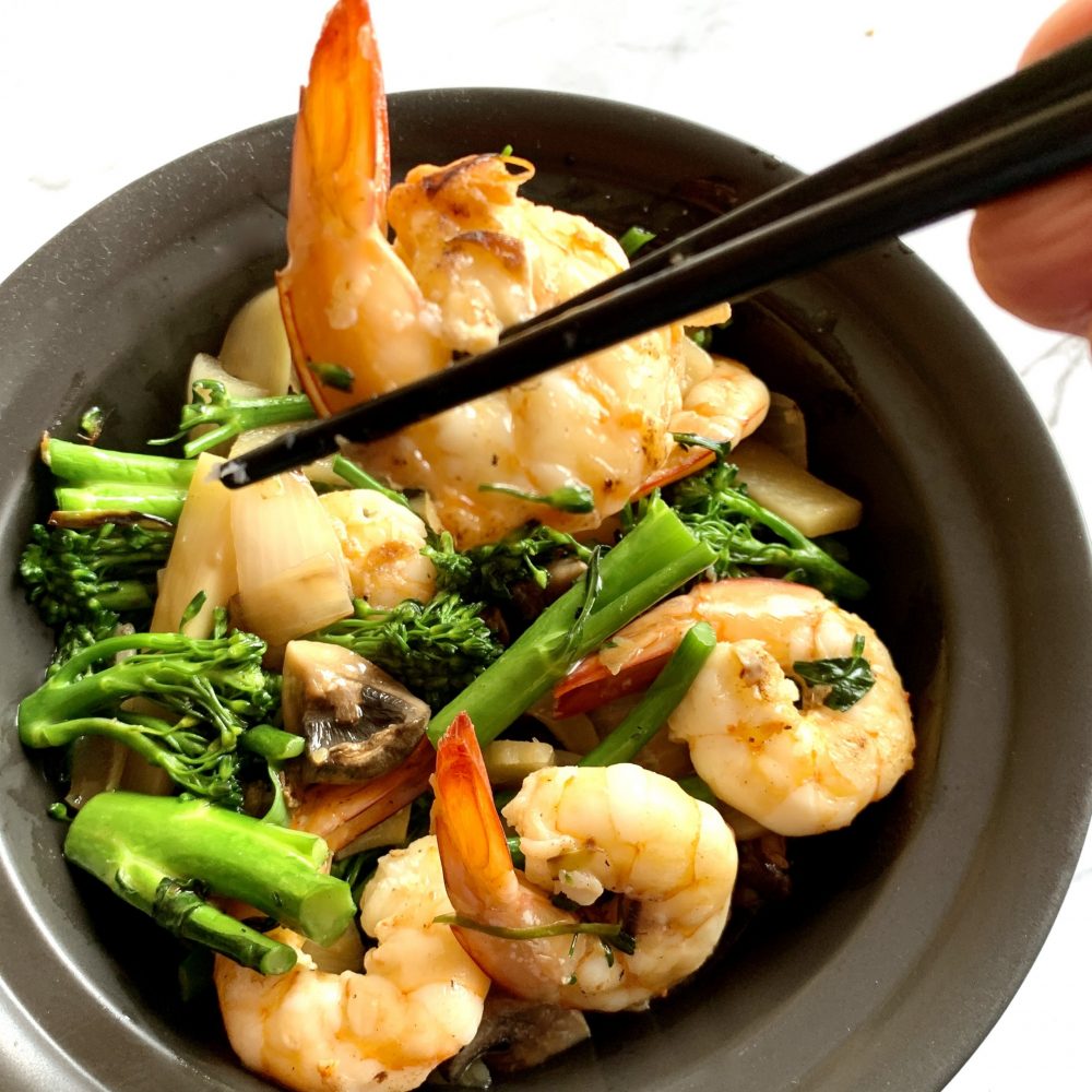 Braised Prawns with Broccolini served with a Chinese style gravy in a black bowl