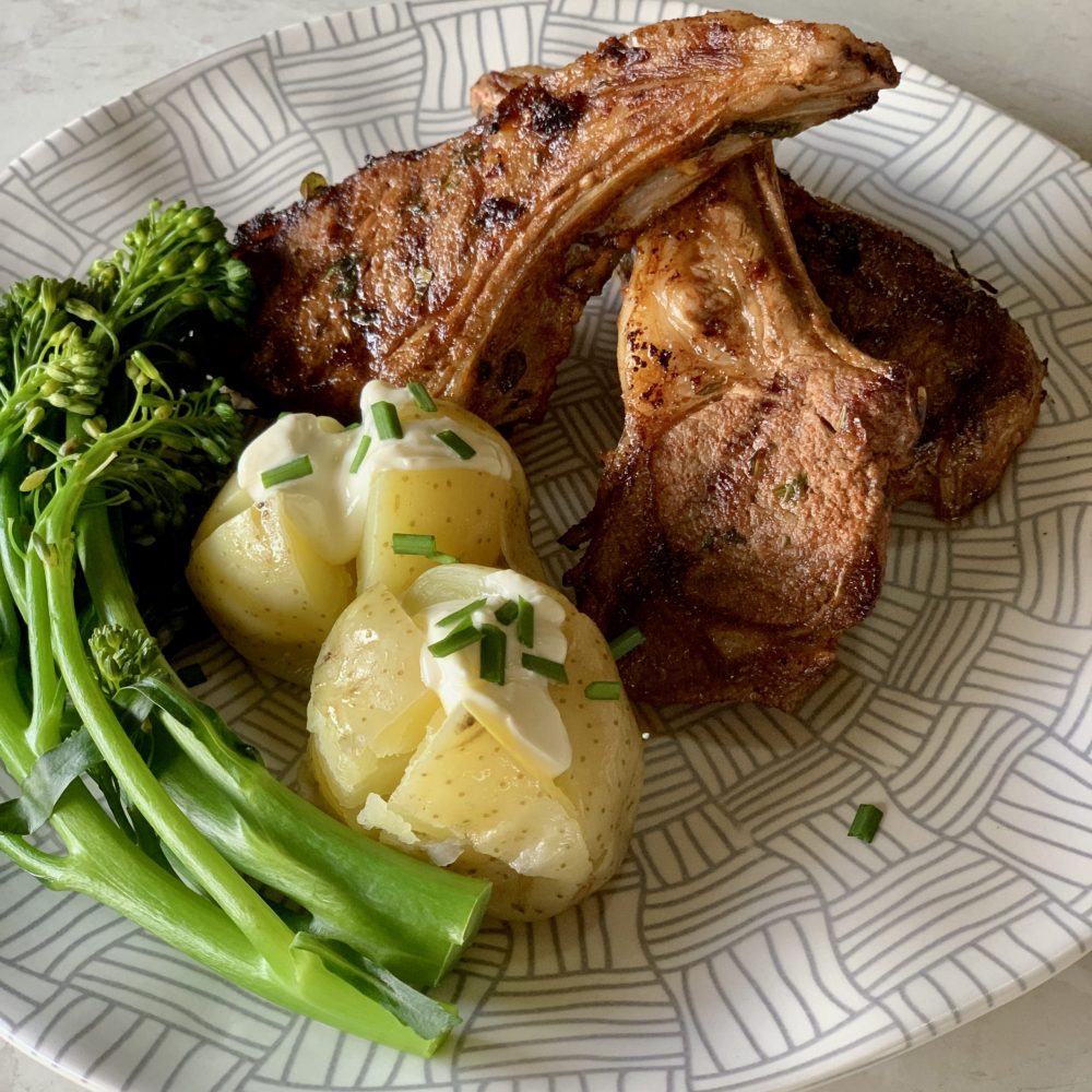 3 lamb cutlets marinating in a combination of fresh oregano, and thyme mixed with smoked paprika, chilli, garlic and brown sugar. Then cooked on a hot grill and served with broccolini and jacket potatoes topped with sour cream and chopped chives