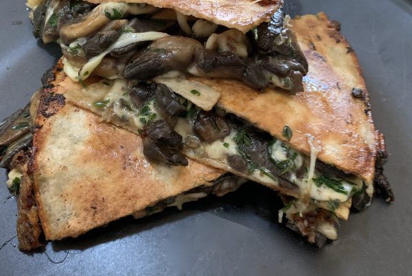 Mushroom Quesadillas: A toasted tortilla turnover filled with pan seared creamy mushroom, basil, baby spinach and melted cheese. Served on a round black plate. by cookingmealsforone.com