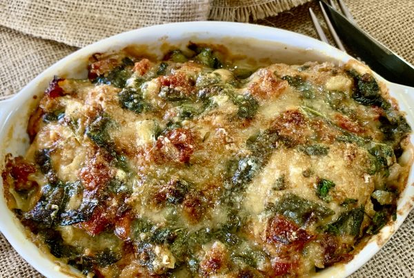 Sun-Dried Tomato Chicken Tray Bake: An oval pie dish filled with chopped cooked chicken thighs, covered in a creamy sauce of garlic, onion, sun-dried tomatoes and baby spinach. Topped with parmesan cheese and baked in oven until golden brown. by cookingmealsforone.com